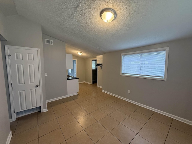 4279 University St, Memphis, TN 38127 - unfurnished room with vaulted ceiling, visible vents, light tile patterned floors, baseboards, and a textured ceiling