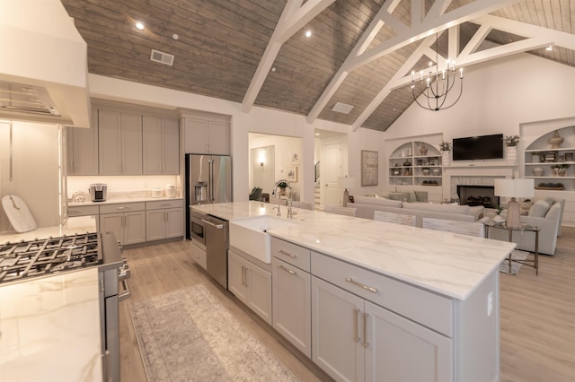 kitchen with high vaulted ceiling, a sink, light wood-type flooring, appliances with stainless steel finishes, and visible vents