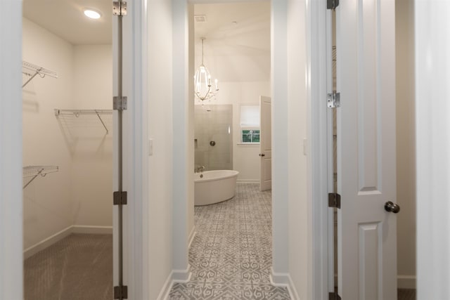 bathroom featuring a walk in closet, a soaking tub, and baseboards