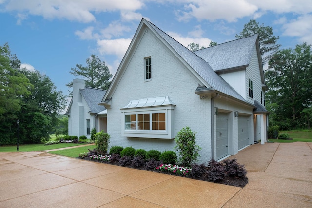 view of side of home featuring driveway, brick siding, a garage, a lawn, and a shingled roof