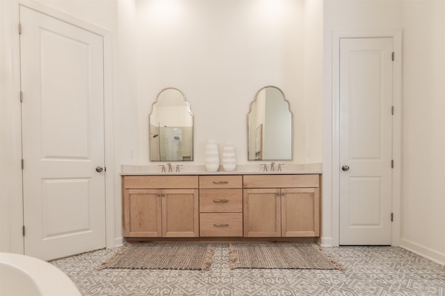 bathroom featuring baseboards, tile patterned floors, a sink, and double vanity
