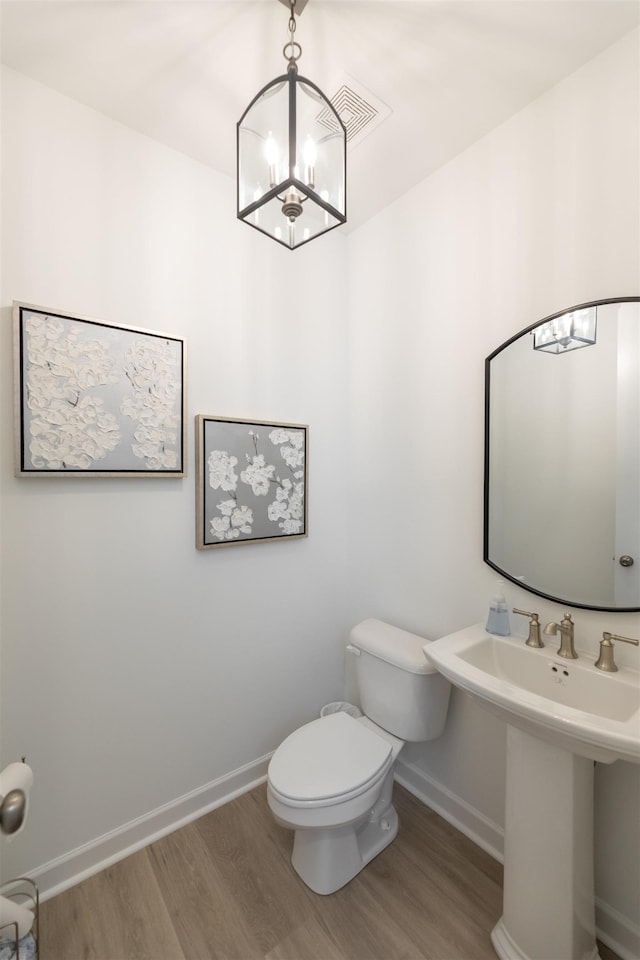 half bathroom featuring baseboards, toilet, wood finished floors, and visible vents
