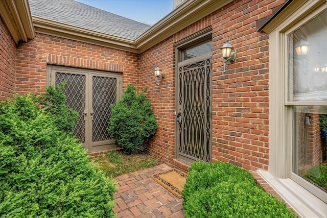 property entrance featuring brick siding and a shingled roof