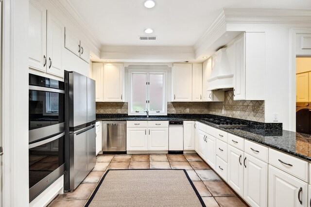 kitchen with custom exhaust hood, white cabinetry, and appliances with stainless steel finishes