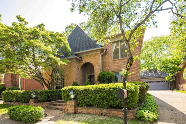 view of front of house with a shingled roof, driveway, brick siding, and a garage