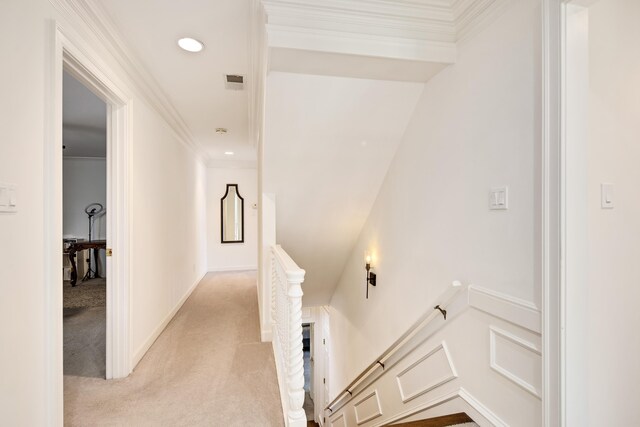 corridor featuring a wainscoted wall, visible vents, ornamental molding, an upstairs landing, and light colored carpet