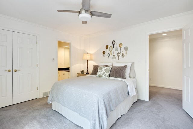 carpeted bedroom featuring ceiling fan, a closet, ornamental molding, and ensuite bathroom