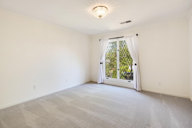 empty room featuring light carpet, baseboards, visible vents, and ornamental molding