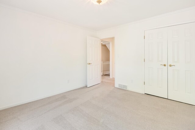 unfurnished bedroom featuring baseboards, ornamental molding, carpet flooring, and visible vents