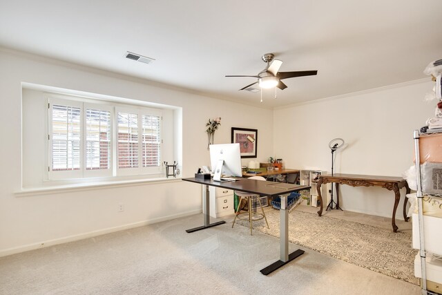 carpeted office space featuring baseboards, visible vents, ceiling fan, and crown molding