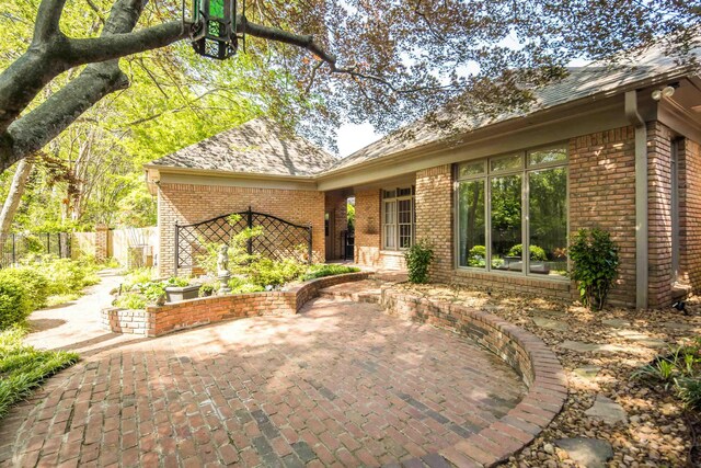 exterior space featuring brick siding, a patio, and fence