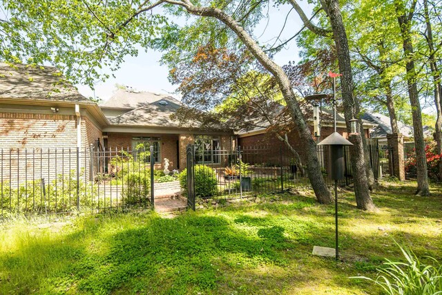 back of house featuring fence and brick siding