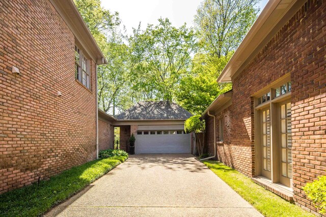 view of side of home featuring brick siding, an attached garage, and driveway