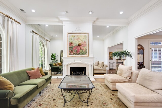 living area featuring a fireplace, wood finished floors, visible vents, and ornamental molding