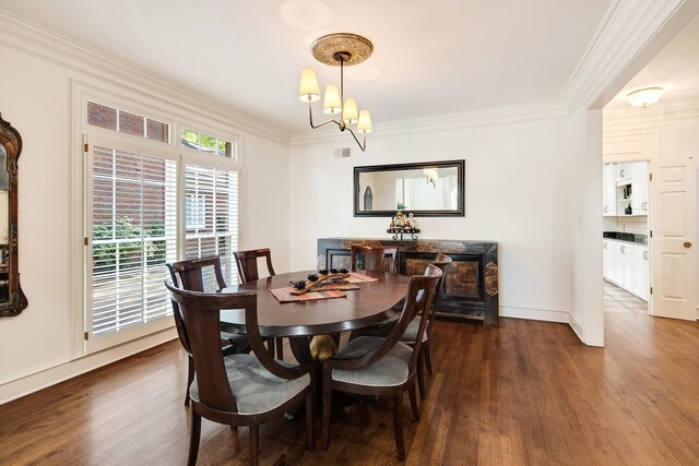dining room featuring dark wood finished floors, visible vents, baseboards, a notable chandelier, and ornamental molding