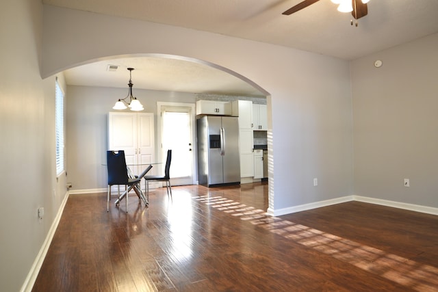 interior space featuring dark wood-style floors, ceiling fan, arched walkways, baseboards, and visible vents