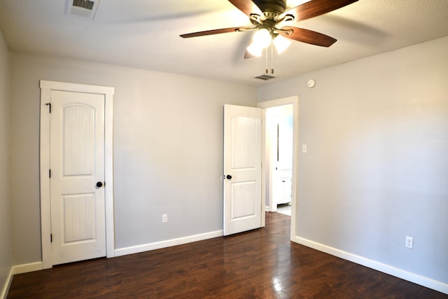unfurnished bedroom with baseboards, visible vents, ceiling fan, and dark wood-style flooring