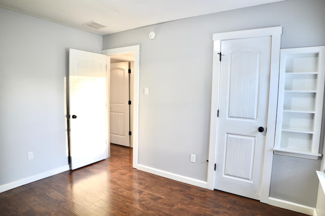 unfurnished bedroom with baseboards, visible vents, and dark wood-style floors