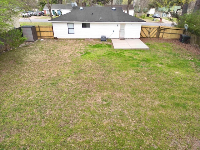 back of property with a storage unit, a fenced backyard, a lawn, an outdoor structure, and a patio