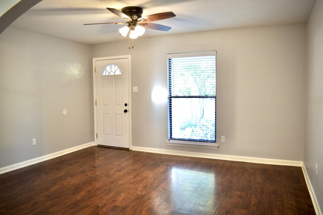 foyer entrance with arched walkways, a ceiling fan, baseboards, and dark wood-style flooring