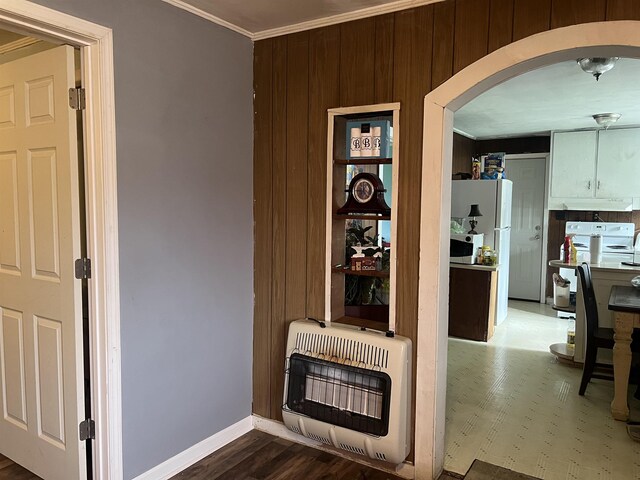 hall with arched walkways, crown molding, baseboards, and heating unit