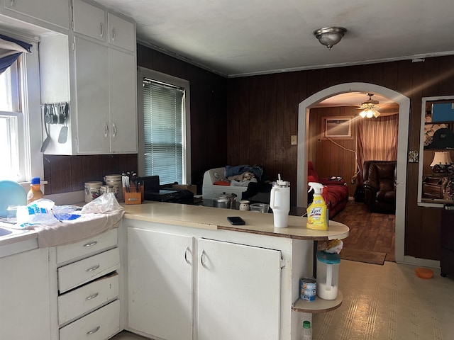 kitchen with white cabinets, arched walkways, wooden walls, and light countertops