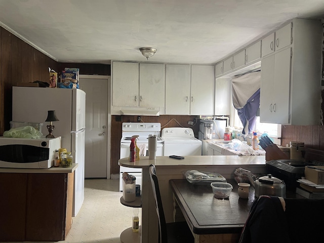 kitchen with stainless steel microwave, a peninsula, washing machine and clothes dryer, and electric stove