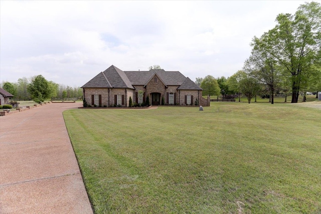 view of front of house with stone siding, brick siding, a front yard, and roof with shingles