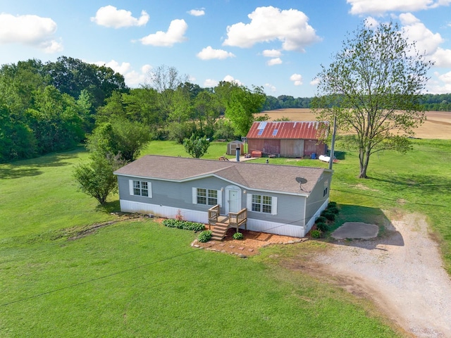 manufactured / mobile home featuring a shingled roof, driveway, and a front yard