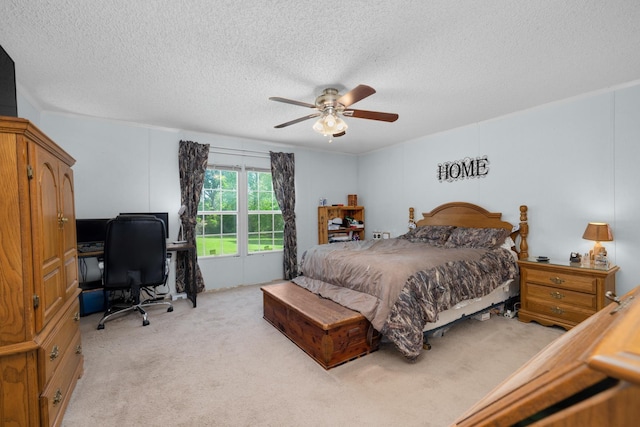 bedroom with light colored carpet, ceiling fan, and a textured ceiling