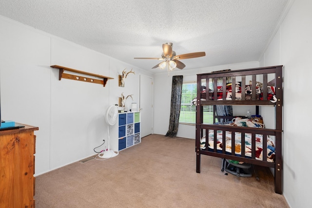 bedroom featuring crown molding, a textured ceiling, carpet flooring, and a ceiling fan