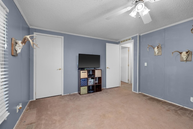 interior space with a textured ceiling, visible vents, ceiling fan, crown molding, and carpet floors