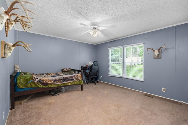carpeted bedroom with a ceiling fan, visible vents, a textured ceiling, and crown molding