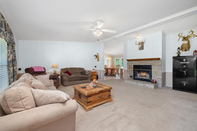 carpeted living room featuring a fireplace, a textured ceiling, and a ceiling fan