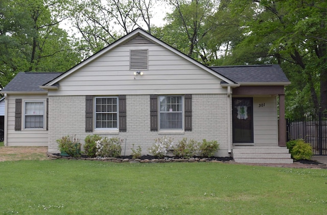 view of front of house with brick siding, entry steps, a front lawn, and fence