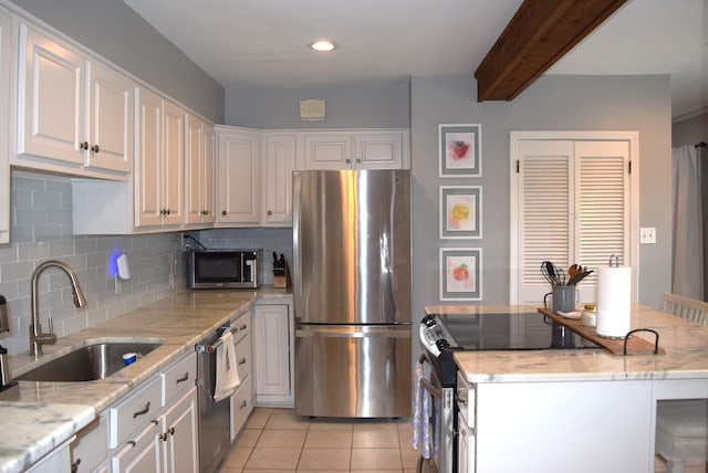 kitchen with backsplash, a sink, light tile patterned flooring, appliances with stainless steel finishes, and white cabinetry