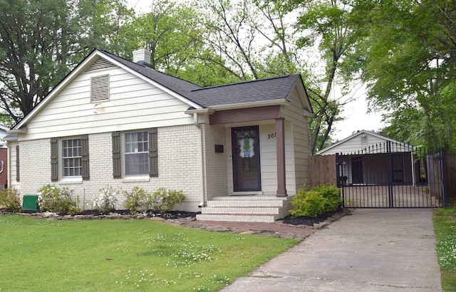 view of front of property featuring a chimney, a gate, driveway, brick siding, and a front yard