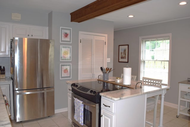kitchen featuring light tile patterned flooring, beamed ceiling, appliances with stainless steel finishes, a breakfast bar area, and white cabinetry