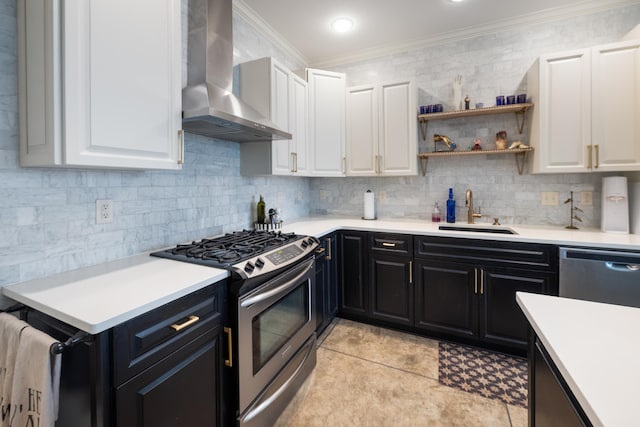 kitchen with dark cabinetry, a sink, wall chimney exhaust hood, crown molding, and appliances with stainless steel finishes