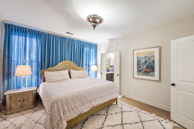 bedroom featuring baseboards, crown molding, ensuite bathroom, and visible vents