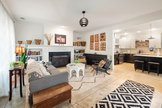 living room featuring light tile patterned floors, crown molding, visible vents, and a fireplace