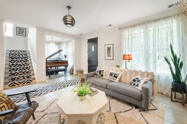 living area with a notable chandelier, a wealth of natural light, stairs, and light tile patterned floors
