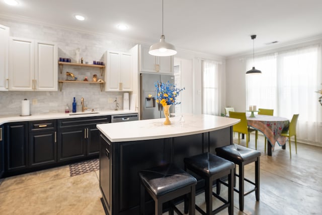 kitchen with a kitchen bar, ornamental molding, stainless steel appliances, and dark cabinetry