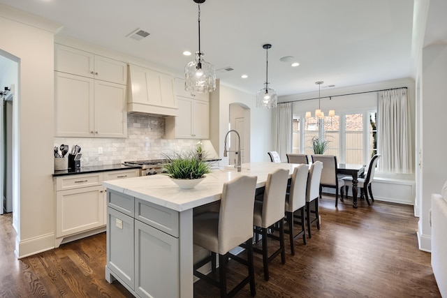 kitchen with recessed lighting, an inviting chandelier, tasteful backsplash, visible vents, and premium range hood