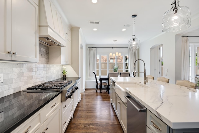 kitchen with recessed lighting, a sink, stainless steel appliances, custom range hood, and arched walkways