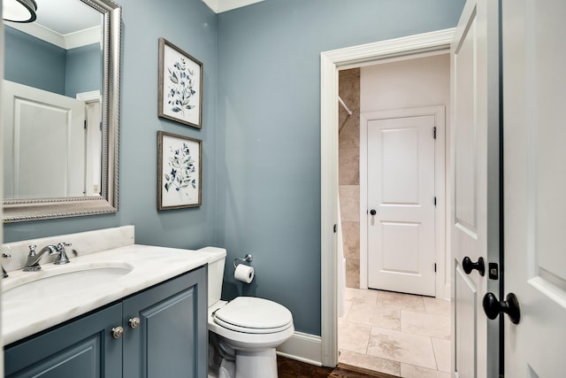 bathroom with toilet, vanity, and baseboards