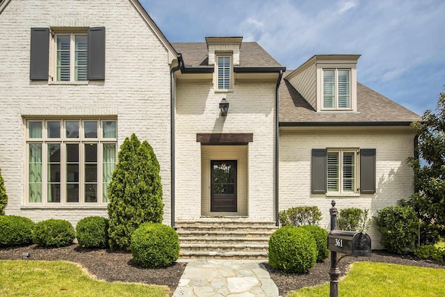 view of front of home featuring a shingled roof, entry steps, and brick siding