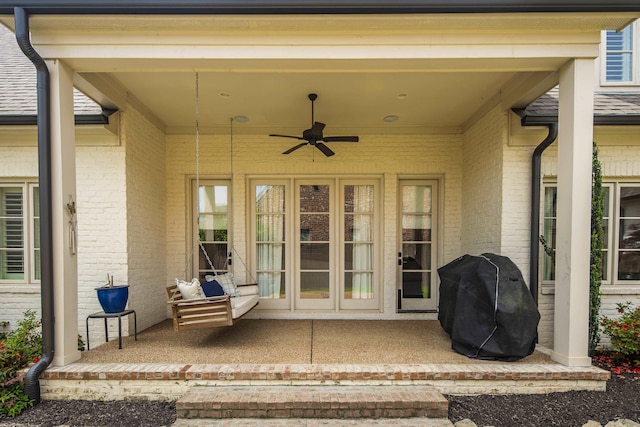 view of exterior entry featuring brick siding and a ceiling fan