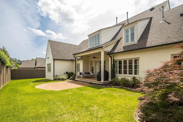 back of house with a patio, a fenced backyard, a lawn, a ceiling fan, and brick siding