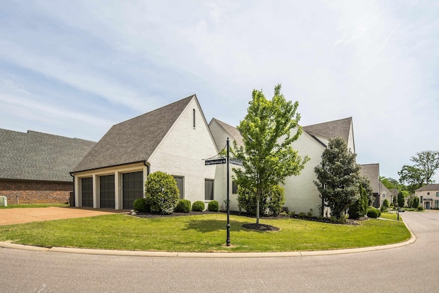 view of side of property with a garage, a shingled roof, concrete driveway, and a lawn